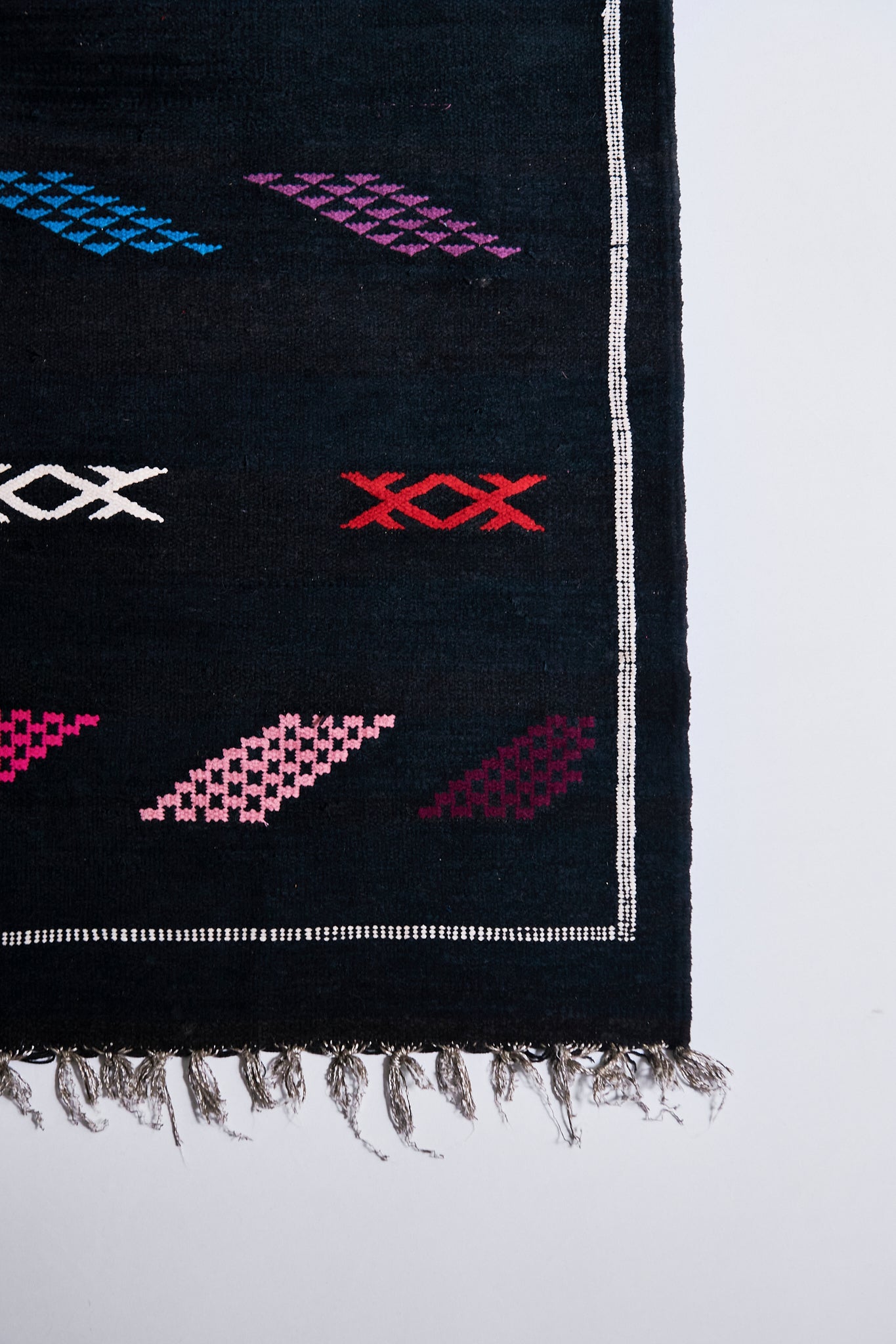 Moroccan Kilim rugs are handmade by women artisans in Morocco to be a very soft wool blend and a thin, flatweave style. Colorful, bright and vibrant colors for your living room, under dining table, or anywhere else for unique, ethnic home decor. Authentic Morocan, Morrocan style rug, black with bright geometric pattern.