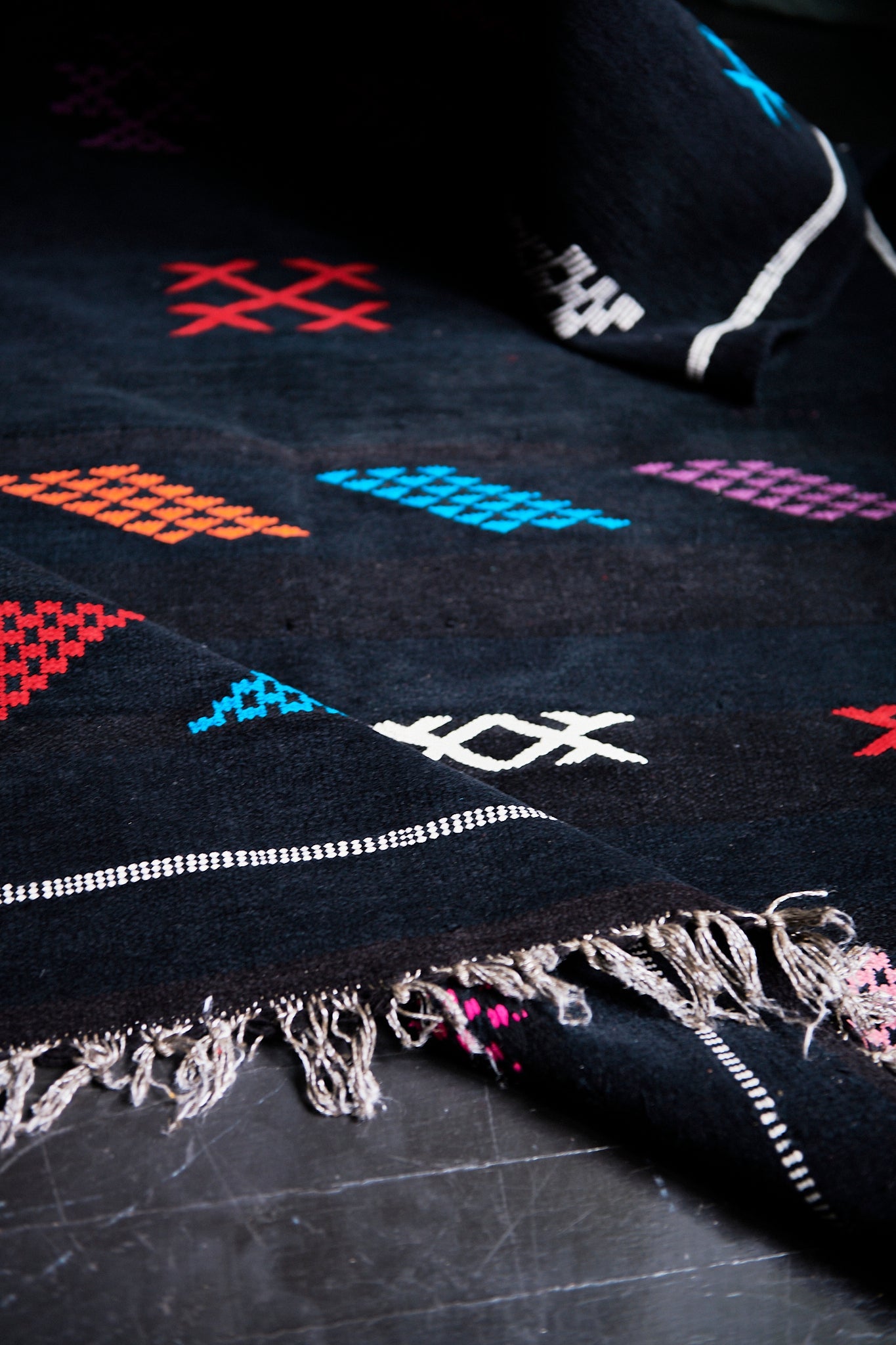 Moroccan Kilim rugs are handmade by women artisans in Morocco to be a very soft wool blend and a thin, flatweave style. Colorful, bright and vibrant colors for your living room, under dining table, or anywhere else for unique, ethnic home decor. Authentic Morocan, Morrocan style rug, black with bright geometric pattern.