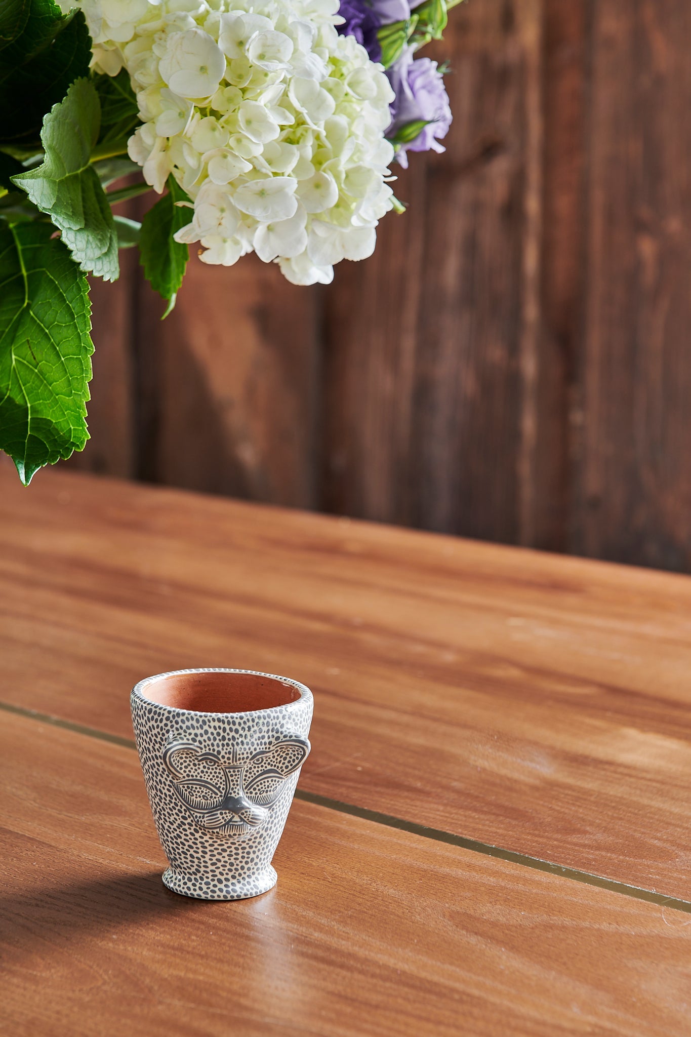 Small cup is a unique jaguar animal head shape that is hand-painted with all over dotted pattern. Made from food safe, natural clay and hand-painted with water based acrylic paint in Mexico. Use as a sipping cup, shot glass or bud vase. Drinkware.